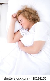 A Young Plus Size Woman Sleeping In Bed.
