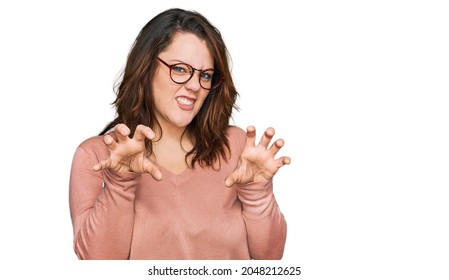 Young plus size woman wearing casual clothes and glasses smiling funny doing claw gesture as cat, aggressive and sexy expression 