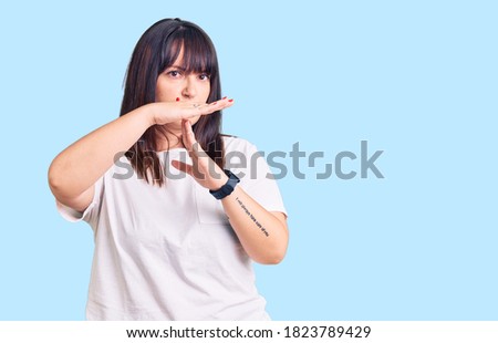 Young plus size woman wearing casual clothes doing time out gesture with hands, frustrated and serious face 