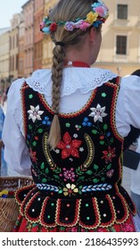 Young Polish Woman, Seen From Behind, Wearing Traditional  Festive Costume. Folklore Textile Clothes. Embroidery Pattern Background.