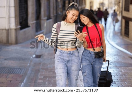 Two young multiethnic women enjoying shopping and taking a selfie