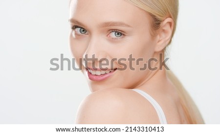 Young positive bolond Caucasian woman looks at camera over her shoulder and smiles against white background | Beauty care commercial concept Stock fotó © 