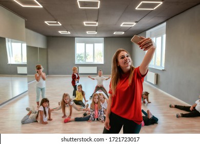 Young And Positive Dance Teacher Making A Selfie With Children While Having Choreography Class. Dance School. Teacher And Kids