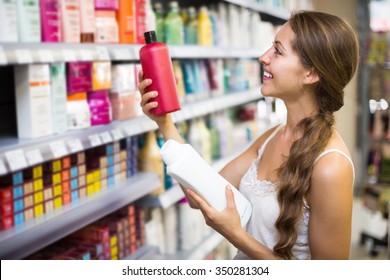 Young Positive Girl Buying Shampoo In Shopping Mall
