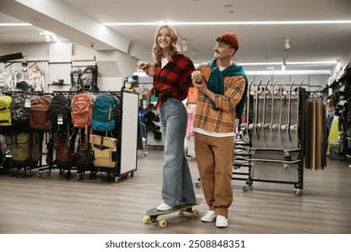 Young positive man and woman couple testing skate board in sport shop - Powered by Shutterstock