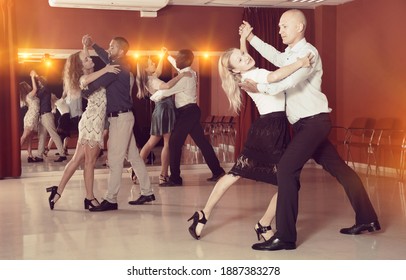Young positive people dancing together slow ballroom dances in pairs ..
