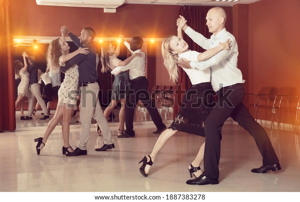 Young positive people dancing together slow ballroom\
dances in pairs ..