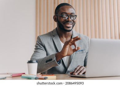 Young Positive Sitisfied African American Businessman In Suit Talking With Business Partner Online, Showing Okay Gesture During Video Call On Laptop Computer, Taking Part In Web Conference