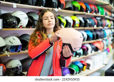 Young Positive Woman Choosing Helmet In A Sports Equipment Store