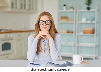 Young positive woman sitting at home, looking at camera and listening to somebody during videocall or teleconference online. Online communication and elearning concept - Shutterstock ID 1815086084