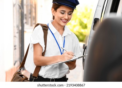 Young Postwoman Writing In Clipboard Near Car