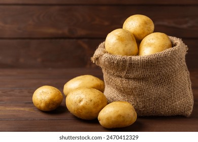 Young potatoes. Fresh potatoes on a wooden background. potato in burlap sack. Harvesting collection. organic, freshly dug potatoes. Agricultural background. Vegan. Vegetables.Place for text.Copy space