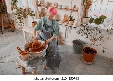 Young potter working on pottery wheel in workroom - Shutterstock ID 2104150763