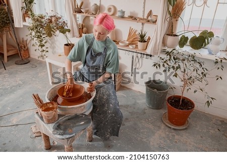 Young potter working on pottery wheel in workroom