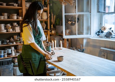 Young pottery workshop owner woman enjoy working with raw clay in studio. Creative artist of potter art prepare earthenware for molding and shaping. Art for relax or self employment small business - Powered by Shutterstock