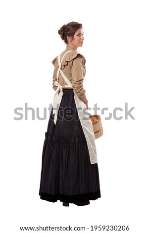 Young prairie woman with apron looking back and holding a basket isolated on white