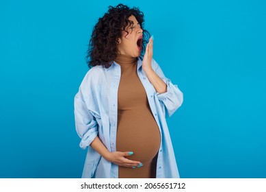 Young Pregnant Arab Woman Standing On Blue Studio Background  Being Tired And Yawning After Spending All Day At Work.