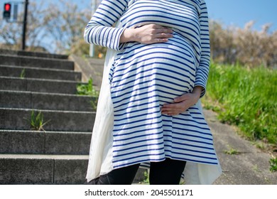 A young pregnant Asian woman goes down the stairs and feels very scared at falling down - Powered by Shutterstock