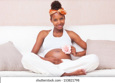 Young pregnant black woman touching her belly - African people
