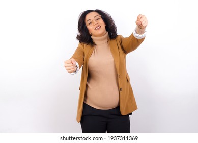 Young Pregnant Businesswoman Wearing Beige Blazer Over White Background Imagine Steering Wheel Helm Rudder Passing Driving Exam Good Mood Fast Speed