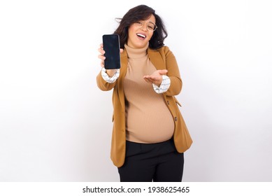 young pregnant businesswoman wearing beige blazer over white background with a mobile. presenting smartphone. Advertisement concept.