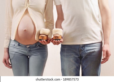 Young Pregnant Couple In Jeans Holding Little Cute Uggs Expecting A Baby Boy In Studio