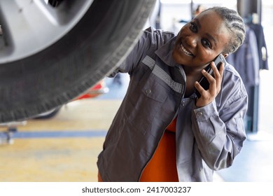 Young pregnant female customer with automotive mechanic worker, happy smiles at maintenance garage, talking to her mobile phone, repair auto industry. Selective Focus - Powered by Shutterstock