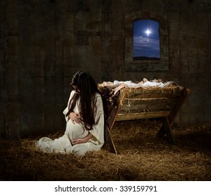 Young pregnant Mary praying leaning on manger on Christmas Eve