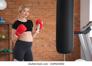 Joven embarazada en guantes de boxeo en el gimnasio