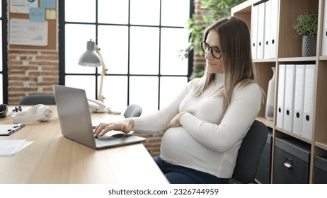 Young pregnant woman business worker using laptop touching belly at office - Powered by Shutterstock