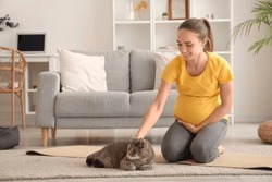 Young Pregnant Woman With Cat Sitting On Yoga Mat At Home
