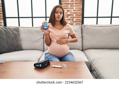 Young pregnant woman checking blood sugar looking at the camera blowing a kiss being lovely and sexy. love expression. 