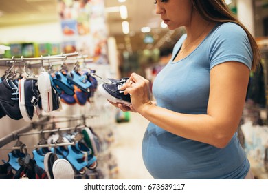 Young Pregnant Woman Checking And Buying Some Stuff For Her Baby. Selective Focus On Hand.