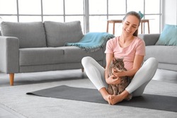 Young Pregnant Woman With Cute Cat Sitting On Yoga Mat At Home