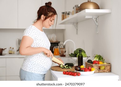 Young pregnant woman cutting fresh vegetables for salad in kitchen - Powered by Shutterstock