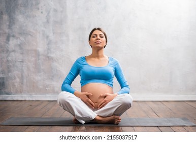 Young Pregnant Woman Doing Yoga Exercises And Meditating At Home. Health Care, Mindfulness, Relaxation And Wellness Concept.