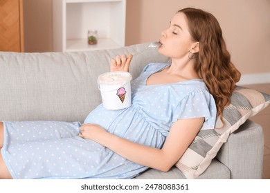 Young pregnant woman eating ice cream on sofa at home - Powered by Shutterstock