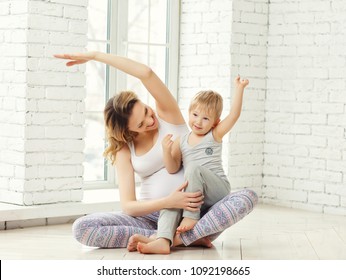 A young pregnant woman engaged in fitness and yoga with the chil