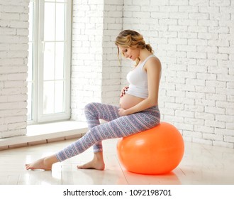 A young pregnant woman engaged in fitness on the fitball.
