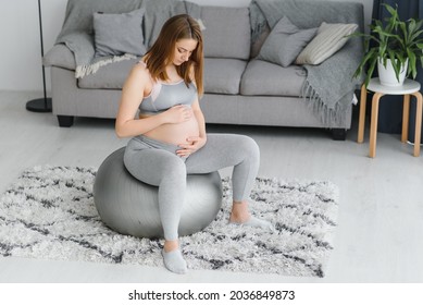 Young pregnant woman exercising yoga with fit ball at home. Healthy sports pregnancy concept