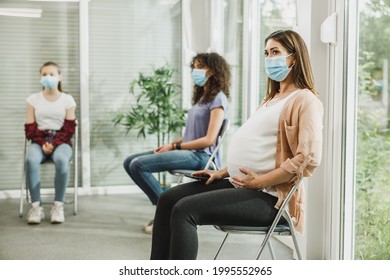 Young Pregnant Woman With A Face Mask Sitting In A Waiting Room And Wait Gynecologist Check Up.
