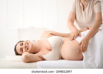 Young pregnant woman getting massage by therapist in spa salon - Powered by Shutterstock