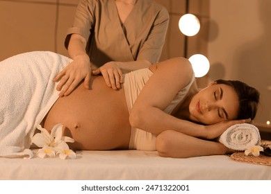 Young pregnant woman having massage in dark spa salon - Powered by Shutterstock