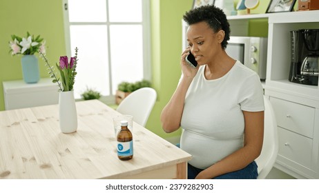 Young pregnant woman having medical phone consultation sitting on table at dinning room - Powered by Shutterstock