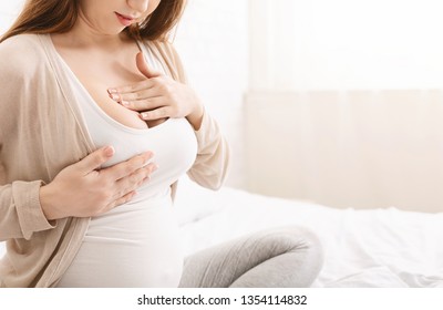 Young pregnant woman having painful feelings in breast, massaging herself, panorama with free space