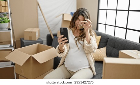 Young pregnant woman having video call holding key at new home - Powered by Shutterstock