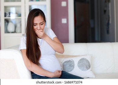 Young Pregnant Woman Having Vomit Up Morning Sickness Sitting On Sofa At Home. Asian Pregnancy  Unwell Suffering With Nausea. Expecting Problem