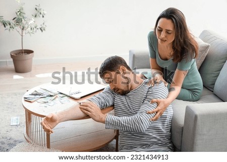 Young pregnant woman with her addict husband at home. Domestic violence concept