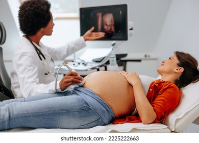 A young pregnant woman is at her doctors office lying on the bed while the doctor is doing an ultrasound for her. - Powered by Shutterstock