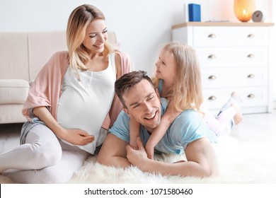 Young Pregnant Woman With Her Family At Home